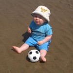 Ben sat on the wet sand with his ball